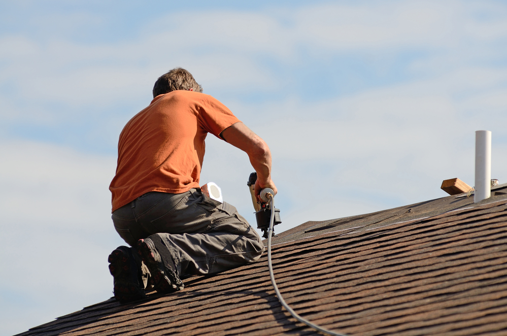 Building contractor putting the asphalt roofing on a large commercial apartment building development.