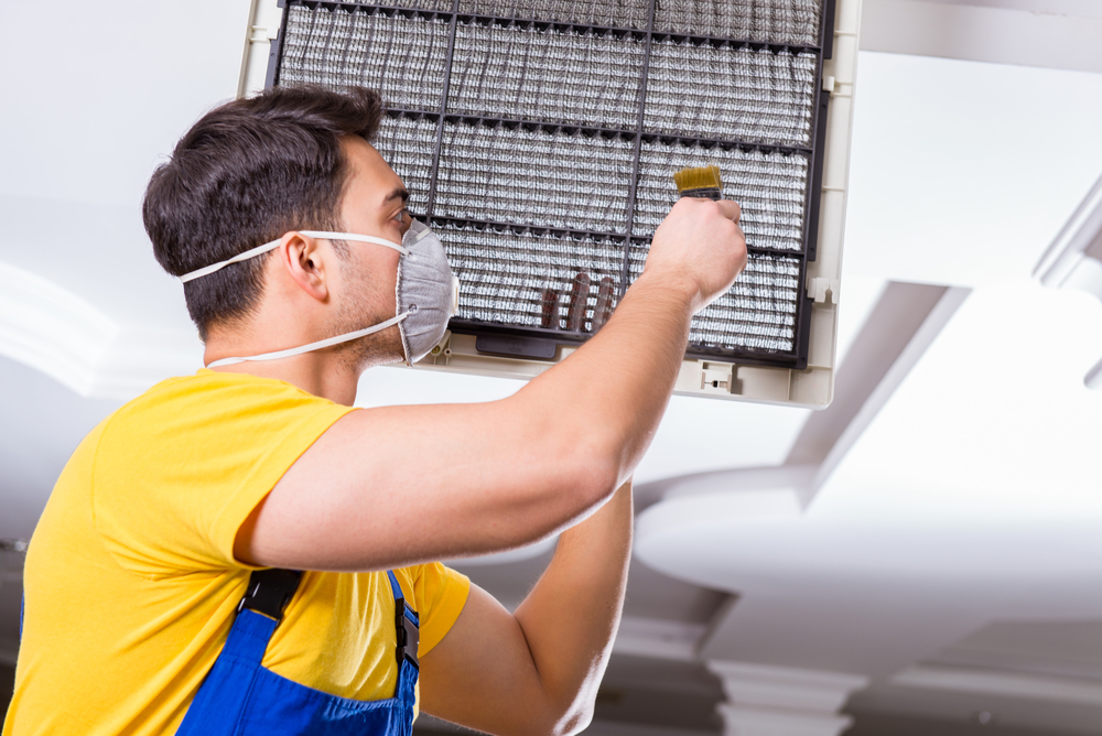 Cleaning ceiling HVAC unit.