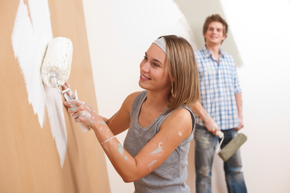 Young couple painting a wall in their home.