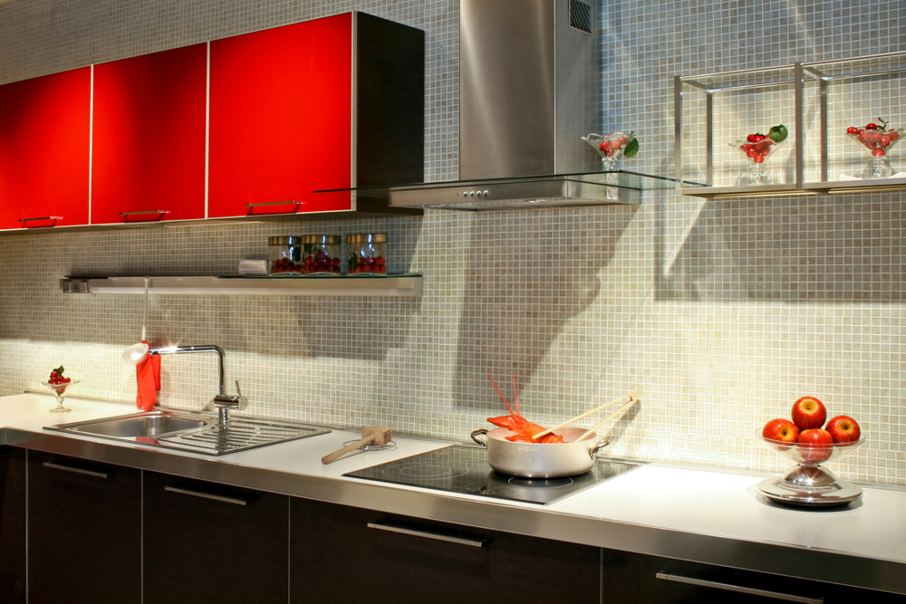 A kitchen with red cabinets and a tiled back splash.