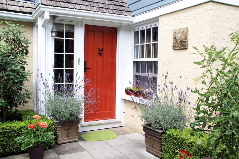 A home with front door painted red surrounded by plants.