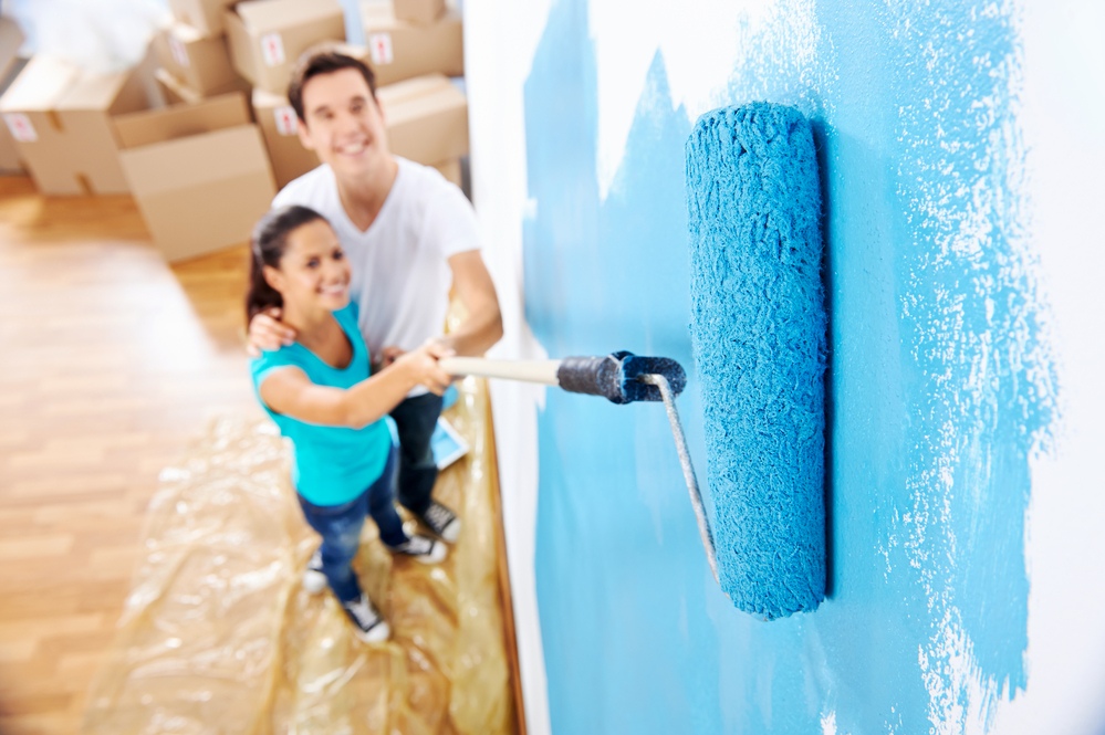 A couple painting a room blue.