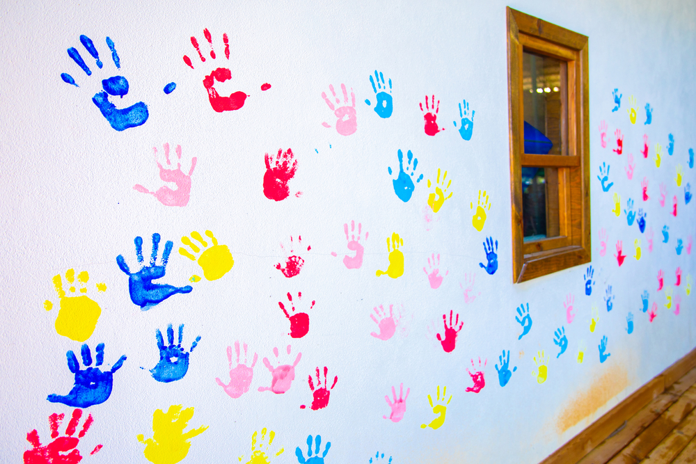 A white bedroom wall covered in a family's painted hand prints.